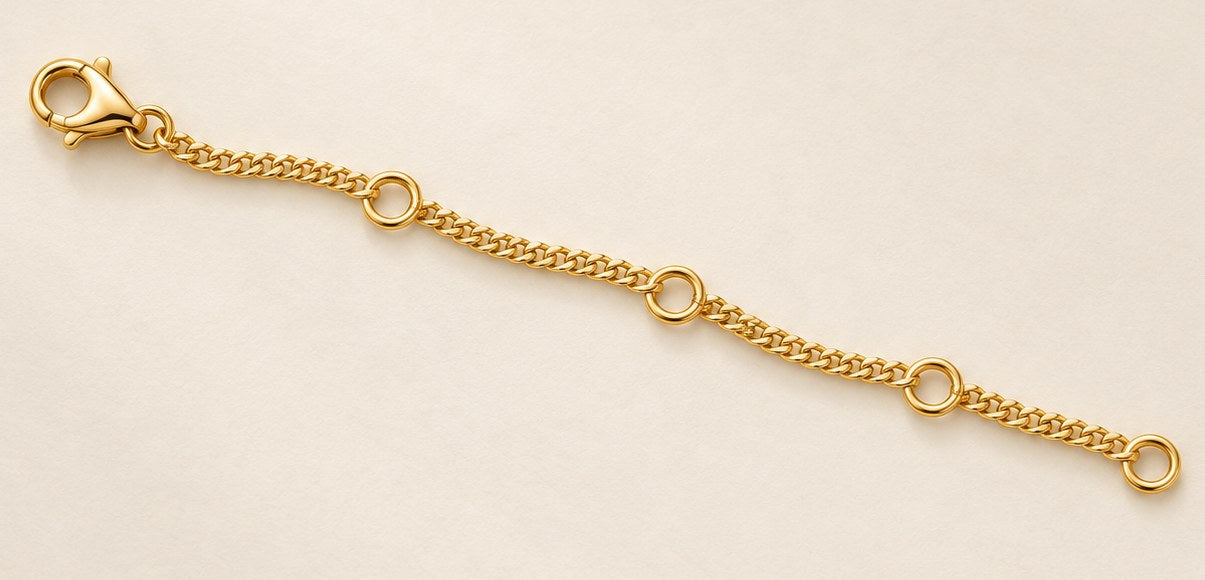 The 4-inch extension chain in 18ct yellow gold, laid flat, lobster clasp at one end and four adjustment loops along its length