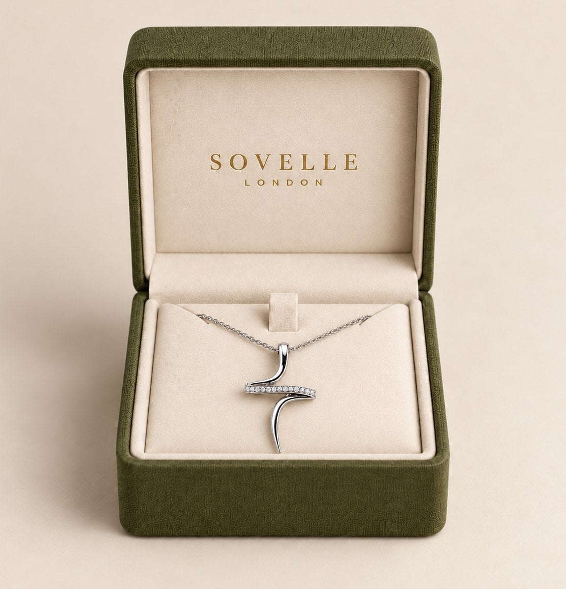 The pendant box open with the white gold cross pendant and chain laid in the cream suede well, the mark foiled inside the lid